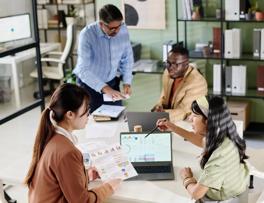 Payroll specialists reviewing reports with a client around an office table
